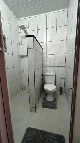 a bathroom with a toilet and a tiled wall at Casa no Centro de Prado in Prado