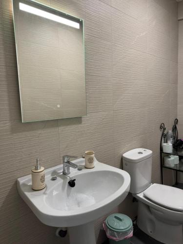 a bathroom with a sink and a toilet and a mirror at Berta Home in Mota del Cuervo