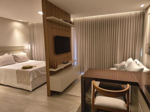 a bedroom with a bed and a desk and a television at Píer 135 Escarpas in Capitólio