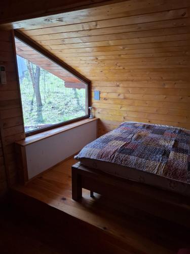 a bedroom with a large window in a log cabin at Cabana trenulețelor in Lunca Mare