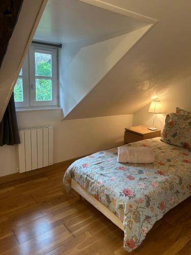a bedroom with a bed with a bedspread and a window at Duplex in Honfleur