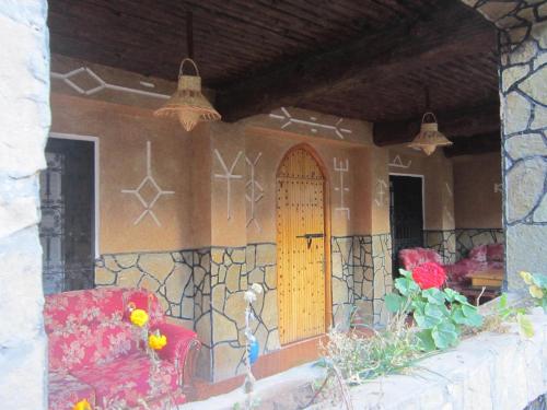 a house with a red chair and a door at La Petite Gorge, Hôtel & Restaurant Todra Gorge in Tinerhir