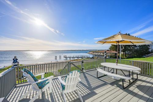 a deck with two chairs and a table and an umbrella at Cape Cod Waterfront with Stunning Views in Buzzards Bay