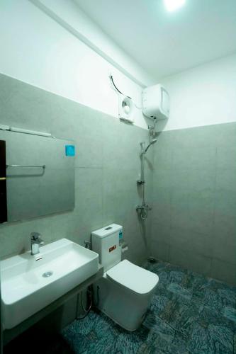 a bathroom with a sink and a toilet and a mirror at Prime Inn Kandy in Kandy