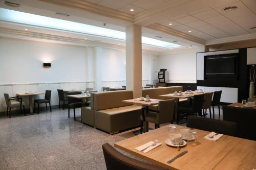 une salle à manger avec des tables, des chaises et un écran dans l'établissement Hostal Carlos III, à Getafe