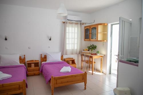 a bedroom with two beds and a kitchen with a table at Fay's Studios Leros in Lakkíon