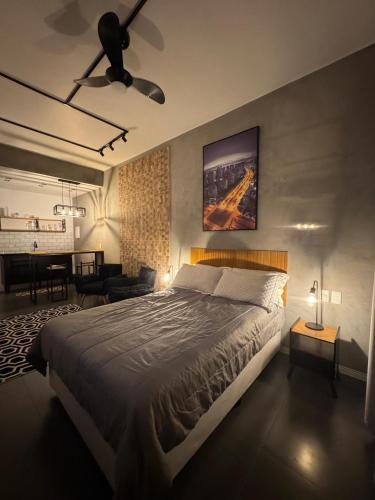 a bedroom with a large bed and a living room at Studio Industrial in Niterói