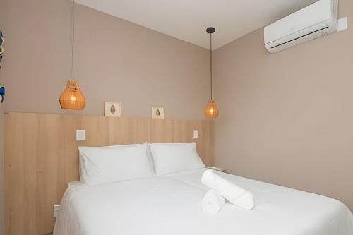 a bedroom with a bed with white pillows and two lights at Sea View + Pool | Cliffs Mar 209 in Pipa