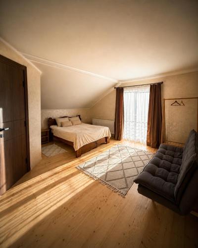 a bedroom with a bed and a couch and a window at ЛІДІЯ in Yasinya