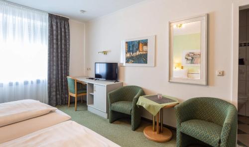 a hotel room with a bed and a desk and chairs at Hotel Keller in Kreuztal