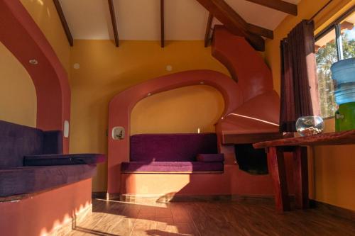 a living room with a purple couch in a room at Cabaña Los Guapurús in Samaipata