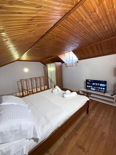 a large bed in a room with a wooden ceiling at Xhoni House in Elbasan