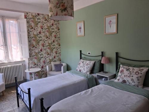 a bedroom with two beds and a chair at Villa Rosalena in Bagni di Lucca