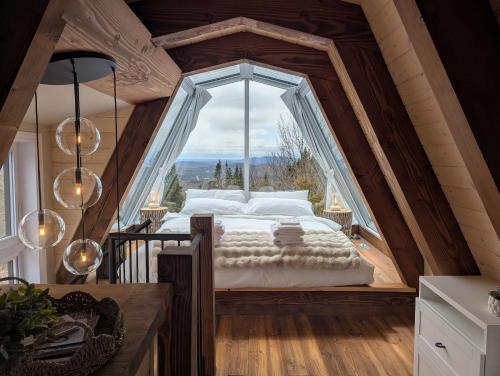 a bed in a room with a large window at Montagne le Maelström in Lac-Beauport