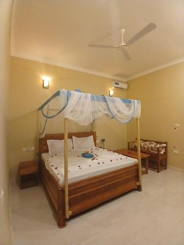a bedroom with a wooden bed with a canopy at Sun house kendwa beach in Kendwa