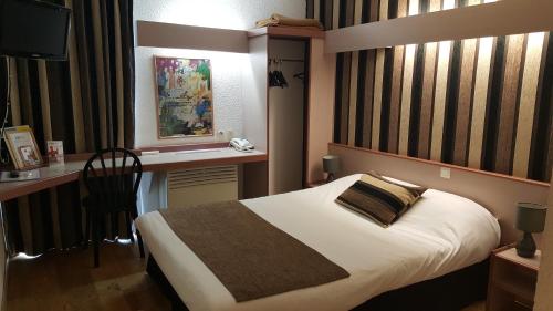 a bedroom with a bed and a desk and a television at Hôtel Eclipse in Magnanville