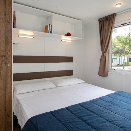 a bedroom with a bed with a blue and white blanket at Camping Klaus in Cavallino-Treporti