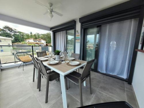 a dining room with a table and chairs and windows at Le léza - Terrasse et plage à 1 min in Les Trois-Îlets