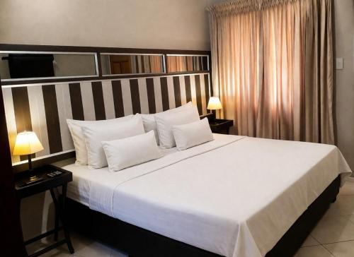 a bedroom with a large bed with white sheets and pillows at Gaecho Guesthouse in Thaba Nchu