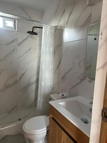 a white bathroom with a toilet and a sink at Mamá María Surf House in Puerto Chicama