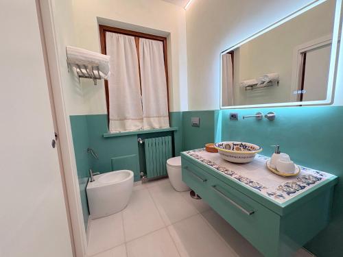 a bathroom with a sink and a toilet and a mirror at Alle porte di Spello in Spello
