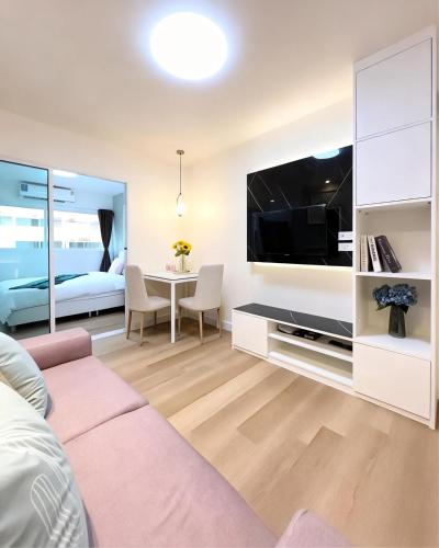 a living room with a couch and a large tv at Impact poppula P1 by เจี๊ยบ in Thung Si Kan