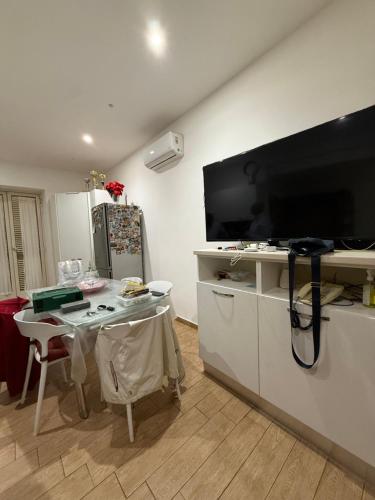 a kitchen with a table and a large screen tv at Serena Guest House in Caserta