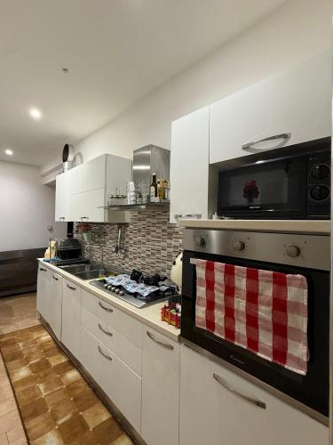 a kitchen with white cabinets and a stove top oven at Serena Guest House in Caserta