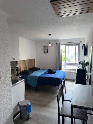 a bedroom with a bed and a table and a kitchen at Les logis de Paray - app 211 in Paray-le-Monial