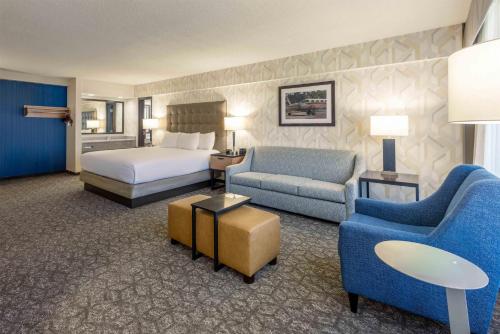 a hotel room with a bed and a couch and chairs at Drury Inn & Suites St. Louis Airport in Edmundson