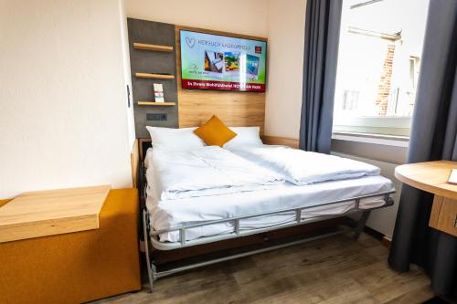 ein Zimmer mit einem Bett mit weißen Laken und einem Fenster in der Unterkunft Hotel am Park Bad Driburg in Bad Driburg