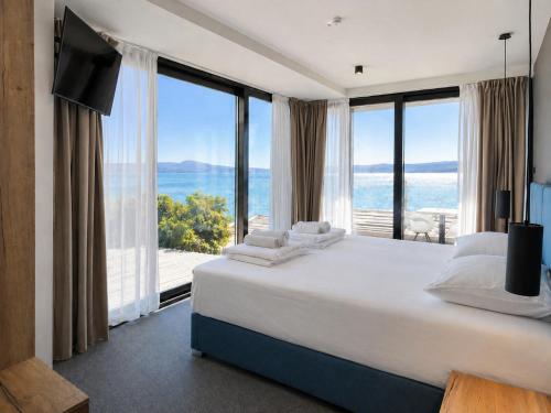 a bedroom with a large bed and large windows at Hotel Millenium deluxe in Selce