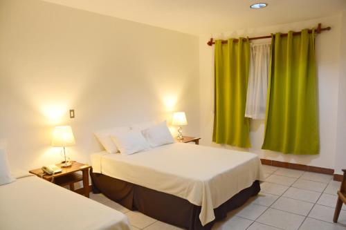 a hotel room with two beds and green curtains at Hotel Europeo in Managua