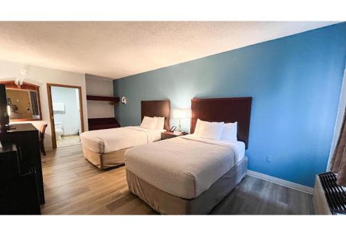 a hotel room with two beds and a blue wall at Studio 6 Suites - Tiffin, OH in Tiffin