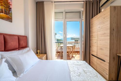 a bedroom with a bed and a balcony with a table at Parid Apartments in Sarandë