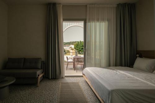 a bedroom with a bed and a chair and a window at FOS Luxury Suites in Nikiti
