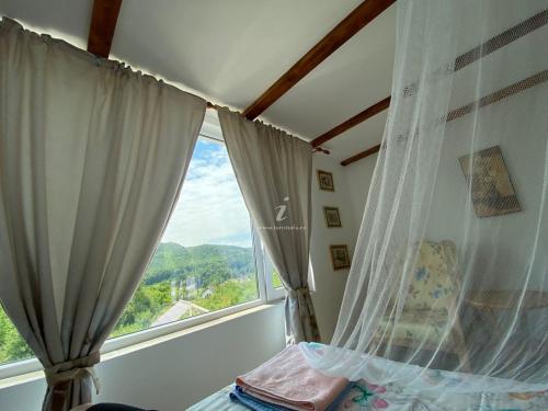 a window with curtains in a bedroom with a view at Casutele Verzi Camera King in Ocnele Mari