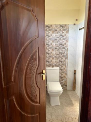 a bathroom with a toilet and a wooden door at Mimi Home Stays in Voi