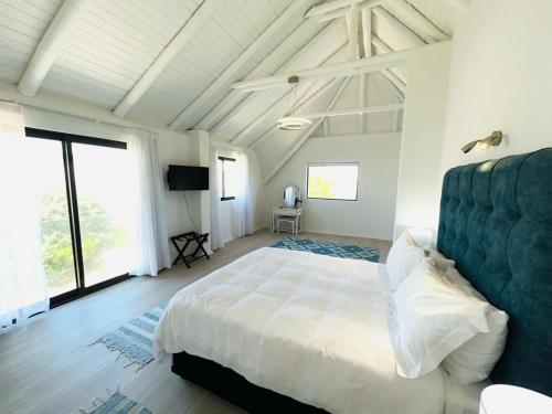a bedroom with a large white bed and large windows at Frank Road At The beach in St Francis Bay