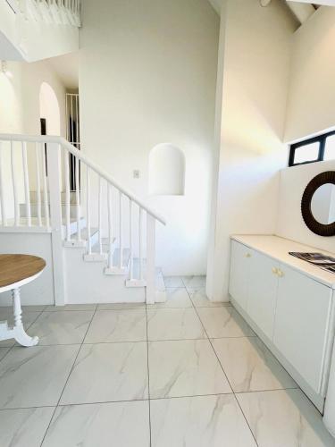 a white room with a staircase and a table at Frank Road At The beach in St Francis Bay