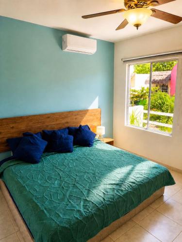 a bedroom with a bed with blue walls and a window at Casa Coral in Puerto Morelos