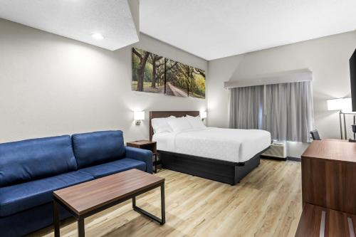 a hotel room with a bed and a couch at Clarion Pointe Jesup in Jesup