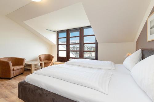 a bedroom with a large white bed and a window at Hotel an der Hörn in Kiel