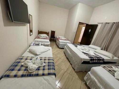 a hotel room with three beds and a flat screen tv at Pousada Imperatriz in Aparecida