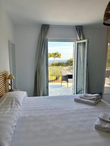 a bedroom with a white bed and a sliding glass door at Elba Essence Suites in Portoferraio