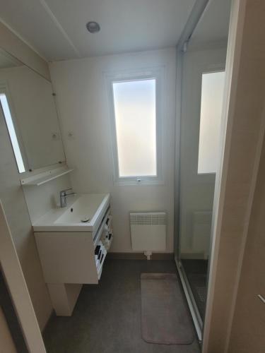 a bathroom with a sink and a window at Mobil-home MJ in Seignosse