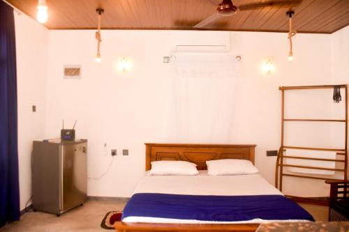 a bedroom with a bed and a refrigerator at Miu Villa in Ahangama
