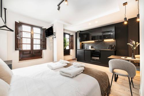 a bedroom with a large white bed and a kitchen at Ando Apartments Boutique in Salamanca
