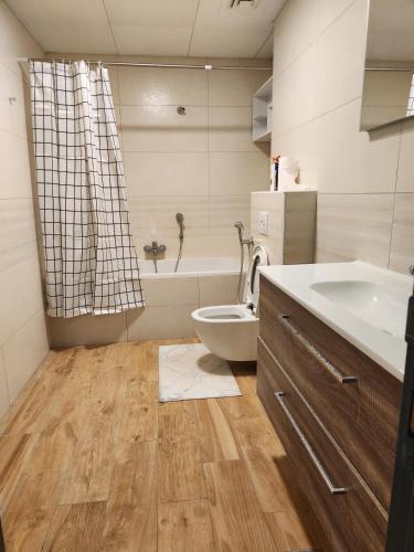 a bathroom with a toilet and a sink and a tub at Premium 2 Bedroom Apartment Near Airport in Muscat