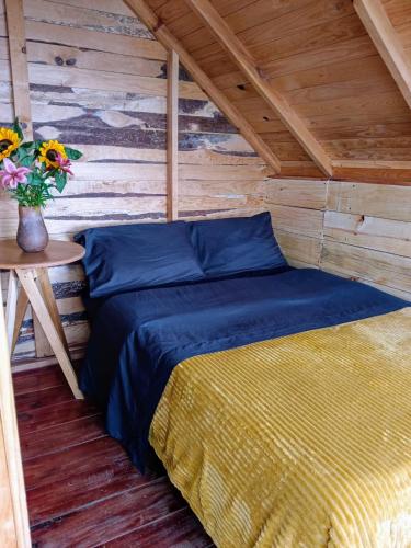 a bed in a wooden cabin with a vase of flowers at Cabañas Alma Serrana in San Jose del Pacifico